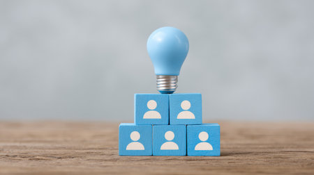 A stack of wooden blocks with a blue light bulb on top. The light bulb is surrounded by people, and the blocks are stacked on top of each otherの素材