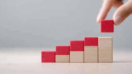 A person is holding a red block and breaking it into smaller pieces. Concept of progress and growth, as the blocks are stacked on top of each otherの素材