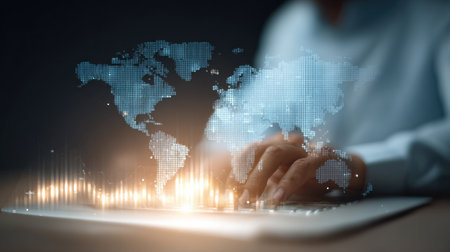 A person is typing on a keyboard with a globe in the background. The globe is surrounded by a blue and white pattern, and the person's hand is hovering over the keyboardの素材