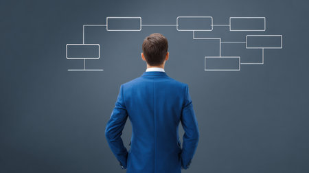 A man in a suit is looking at a diagram on a wall. The diagram is a flow chart with many branches and nodes. The man is deep in thoughtの素材
