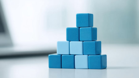 A stack of blue blocks on a table. The blocks are arranged in a pyramid shape. Concept of stability and strength, as the blocks are stacked on top of each other without any wobbling or instabilityの素材