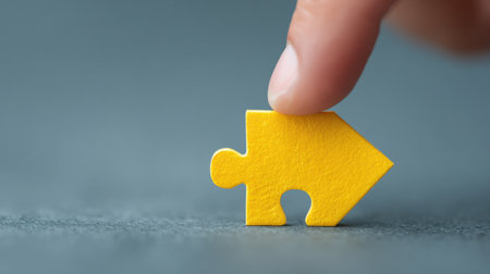 A yellow puzzle piece is held in a hand, with the tip of the finger pointing at it. Concept of curiosity and exploration, as the person is trying to figure out how to fit the piece into the puzzleの素材