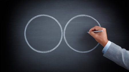 A man is drawing two circles on a blackboard. The circles are connected by a line, which represents the concept of unity or connection. Concept of collaboration and teamworkの素材