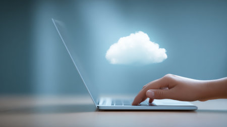 A laptop is open to a screen with a cloud and a finger on it. Concept of technology and productivity, as the person is using the laptop to work or create somethingの素材