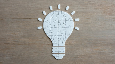 A white light bulb is cut into pieces and placed on a wooden surface. Concept of a light bulb representing a moment of inspiration or a creative sparkの素材
