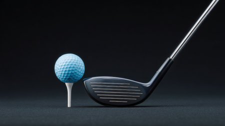 A golf ball and a golf club are placed on a black surface. Concept of focus and concentration, as the viewer is likely to be thinking about the game of golfの素材