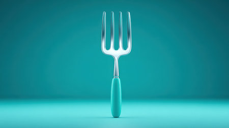 A fork is sitting on a blue background. The fork is silver and has a blue handle. The image has a calm and peaceful moodの素材