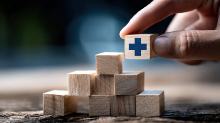 A hand is holding a wooden block with a cross on it, and it is on top of a stack of wooden blocksの素材