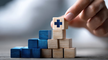 A hand is holding a wooden block with a cross on it, and another wooden block on top of it. The blocks are stacked on top of each other, creating a pyramid shapeの素材