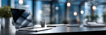 A laptop is open on a desk with a cup of coffee next to it. The scene is set in a modern office with a view of the city. The laptop is turned on and the coffee cup is half fullの素材