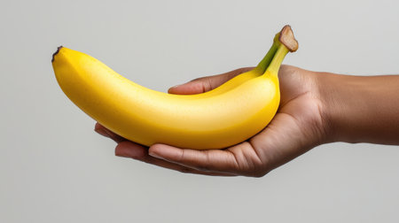A person is holding a banana in their hand. The banana is yellow and he is ripeの素材