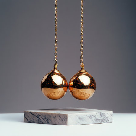 Two gold balls hanging from a chain, one of which is slightly larger than the other. Concept of elegance and luxury, as the gold balls are suspended in mid-air, seemingly weightlessの素材