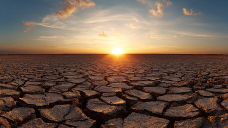A desolate desert landscape with a large sun in the sky. The sun is setting, casting a warm glow over the barren land. The emptiness of the desertの素材