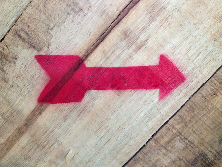 Pointer arrow of red color on wood background.の写真素材