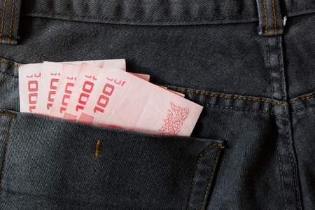 Thailand money including 100 baht in back pocket of a man's black charcoal jeans pocket.の写真素材