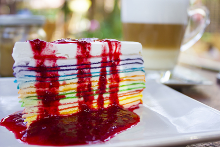 Colorful cheesecake and strawberry syrup on plate at coffee cafeの写真素材