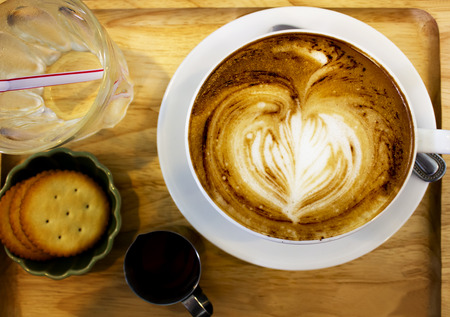 Cup of cappuccino coffee with heart shape latte art on old wood table Background, Latte coffee on old wooden Background tableの写真素材