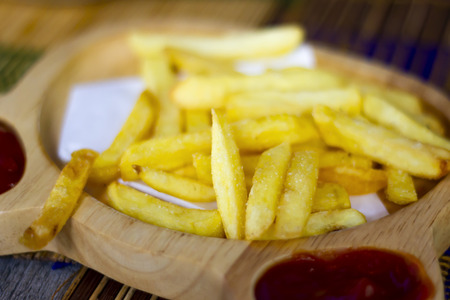 French fries and  ketchup on wood table,  junk food and unhealthy food