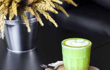 Hot green tea latte with green on wooden.