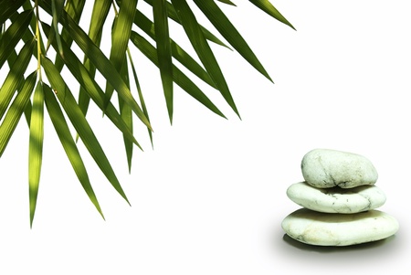 Zen stones pyramid on white background, green leaves bamboo  over itの写真素材