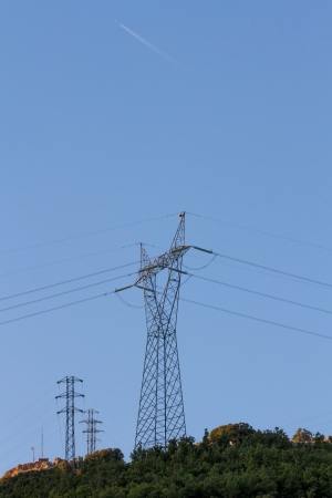 Different towers of power lines on top of a hill jet through the skyの写真素材
