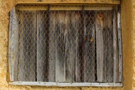  Window of old wooden planks  House of adobe or mud  With metal wire gridの写真素材