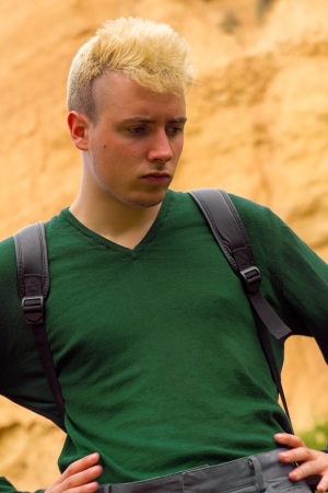 Young caucasion man with dyed blond hair and backpack   Bottom clay cliff 