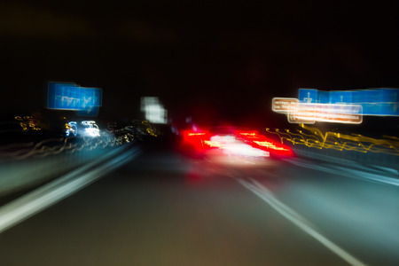 Blurred abstract of night traffic on highway with cars and signage. Painting with lightの写真素材
