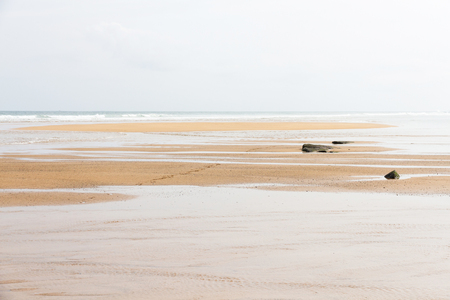 Detail of flat beach with some stone, clear sand wet and the waves of the sea arrivingの写真素材
