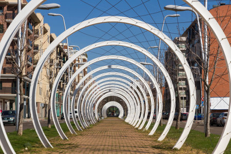 Pedestrian walk through the center of an avenue, protected by a mesh of cables intertwined between white semicircular metal arches that simulate a tunnelのeditorial素材