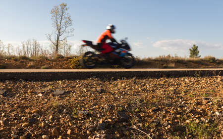Cross sectional view of the asphalt base layer or firm with gravel and asphalt of a road at ground level by which a motorcycle rider on a motorcycle blurred by the movementの写真素材