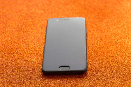 Smartphone mobile phone isolated on bright orange rugged background and fingerprint button and started in the foregroundの写真素材