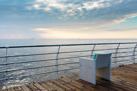 Terrace with a view on sea and sunset. Umbrellas and lounge chair in a sunlight.の写真素材