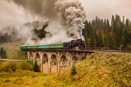 Retro steam train approaches mountainsの写真素材
