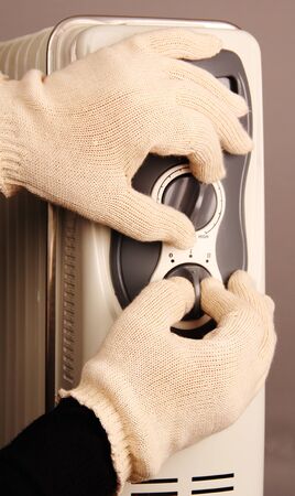 two hands in gloves regulate home oil heater の写真素材