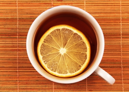 cup of tea with a slice of lemon, top view of the textural brown background の写真素材