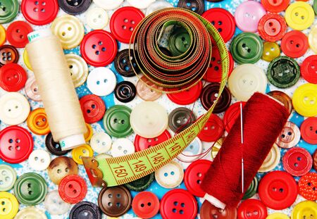 sewing thread, needle, sartorial meter on the background of buttons in different colors 