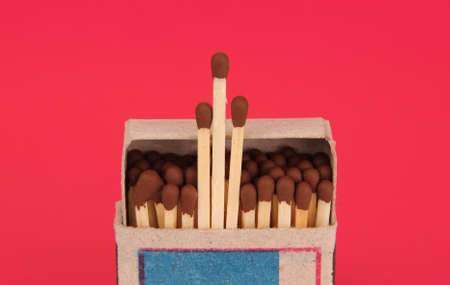 Upright slightly open cardboard box of matches on a red background 