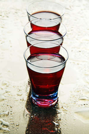 red wine in a transparent glass on a mirror covered with water drops の写真素材