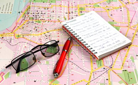On the tourist map of the city are a notebook, pen and glasses の写真素材