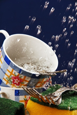 two porcelain tea cups and spoons in the kitchen sink with water の写真素材