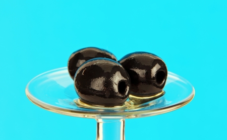 Group of marinated olives on a glass base on a colored background の写真素材