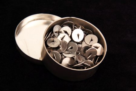 thumbtacks in a round metal box, photo on a dark blue background の写真素材