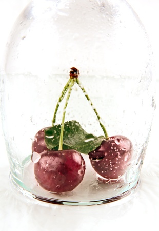wet berries ripe red cherries on a table and in a glass container の写真素材