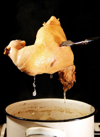 a piece of cooked chicken on a fork over the potの写真素材