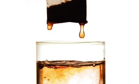 tea bag in a clear glass cup, a drop of tea on the white background.の写真素材