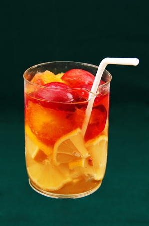 Drink with lemon and plum in a transparent glass on a green background.の写真素材