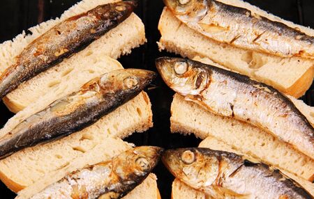 several small fried fish on slices of white breadの写真素材