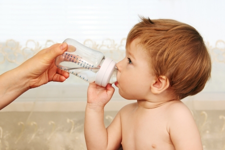 small child drinks water from a bottle with a nipple.の写真素材