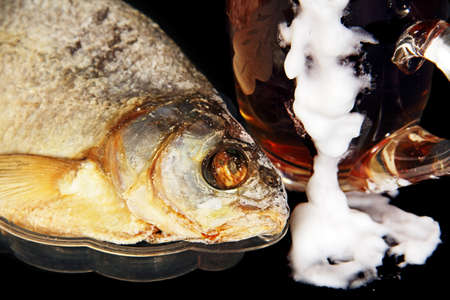 Dried fish on a plate closeup and a beer in a clear glass.の写真素材